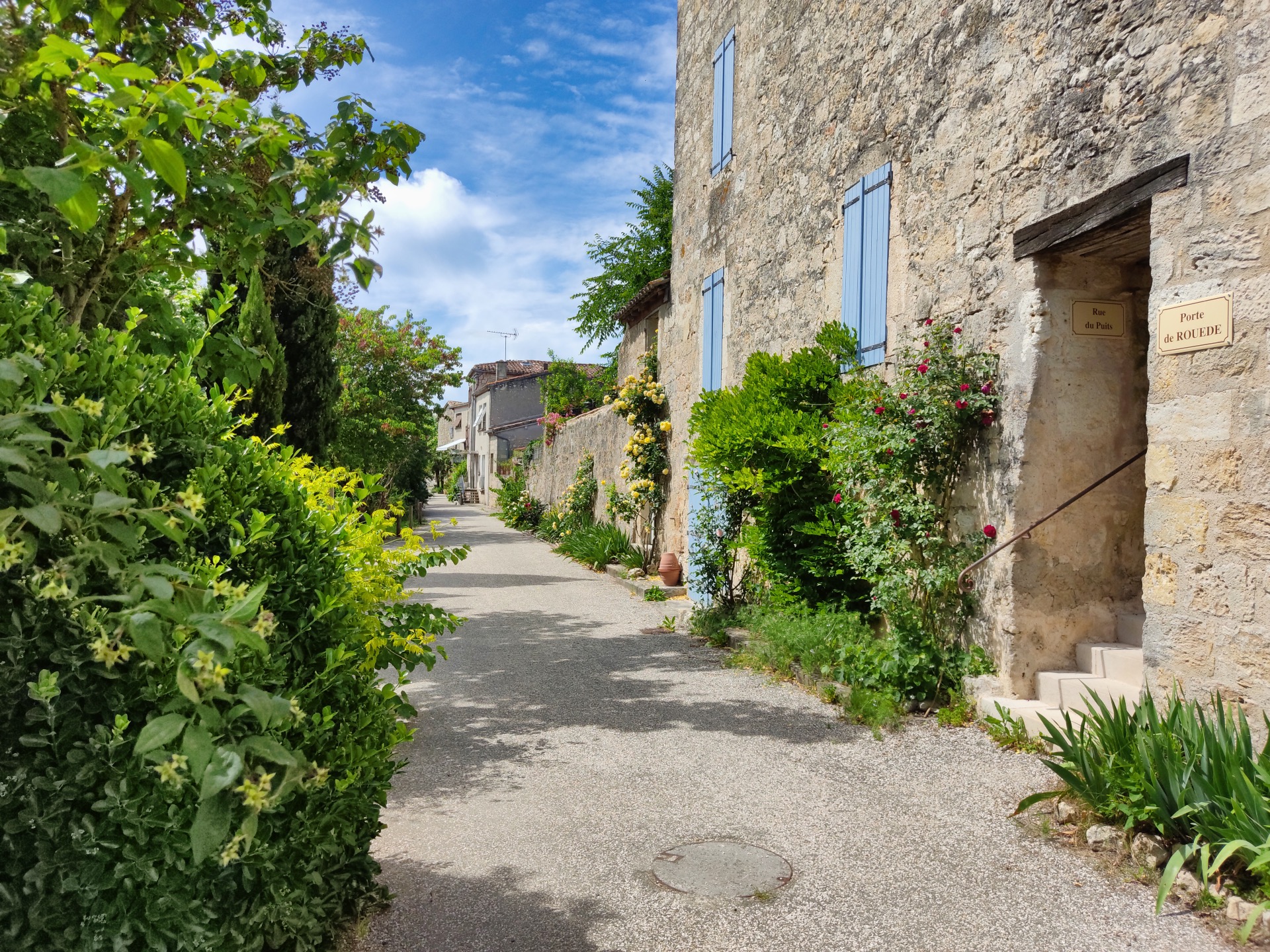 Ruelle de La Romieu avec rosiers grimpants et plaque Porte de Rouède