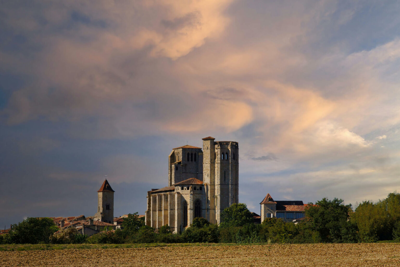 La collégiale de La Romieu sous un ciel doré, au-dessus des champs du Gers