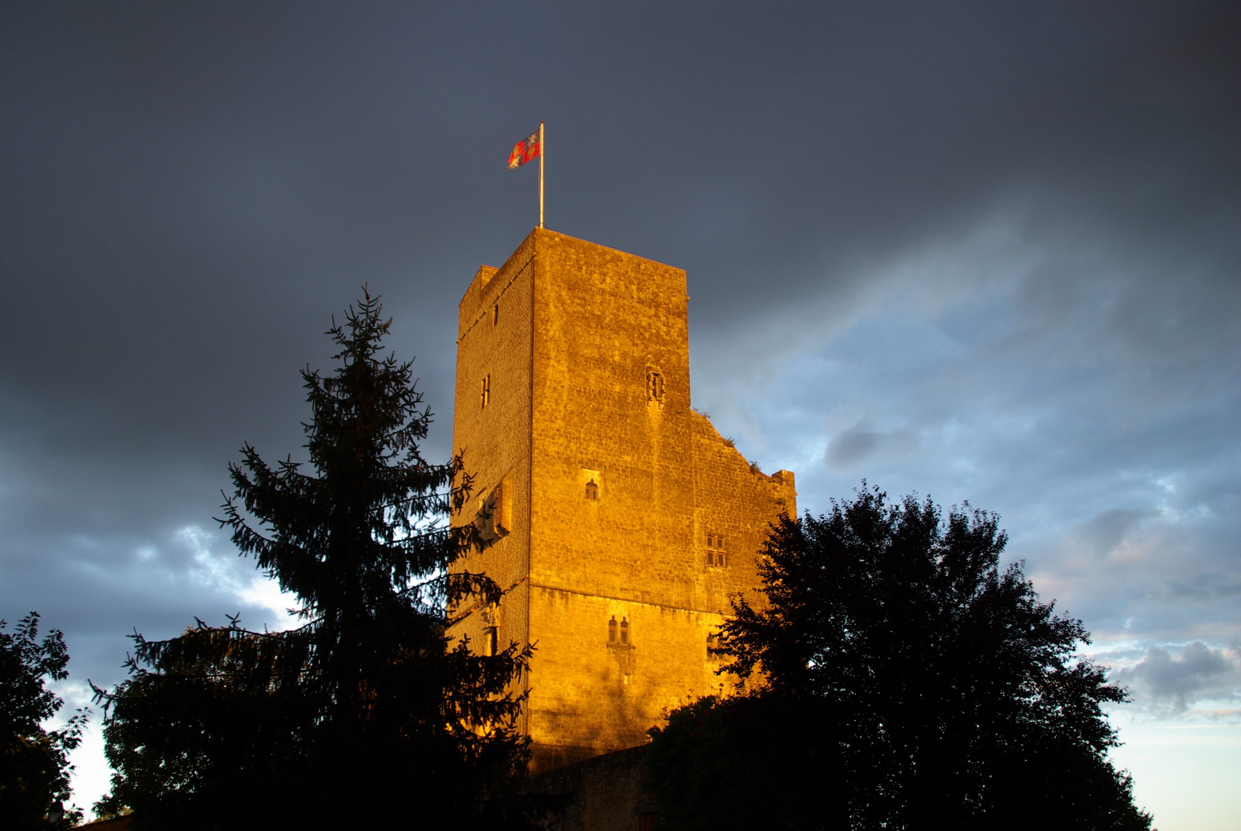 La tour de Termes-d’Armagnac sous une lumière dorée et un ciel d’orage